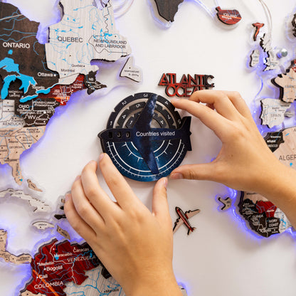 Map with travel stickers and a hand placing a 'Countries visited' sticker on it