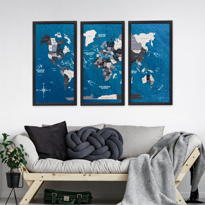 Three framed world maps on a wall above a sofa with decorative pillows and a blanket.