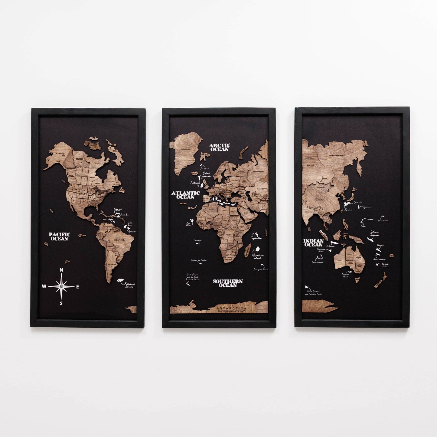 Three framed world maps on a white wall