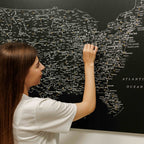 Woman interacting with a large map of the United States on a wall.