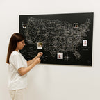 Woman interacting with a large black map of the United States on a white wall.