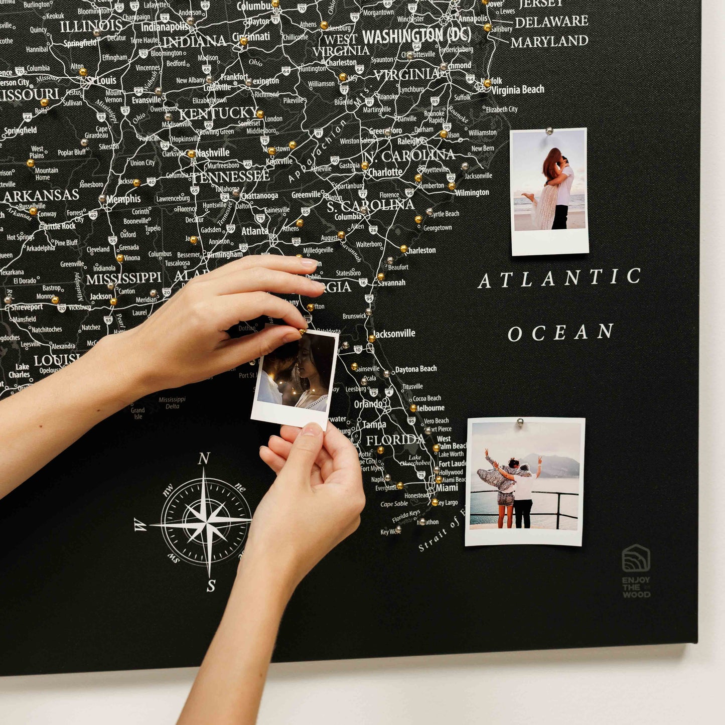 Map of the United States with pins and a person holding photos on a black background