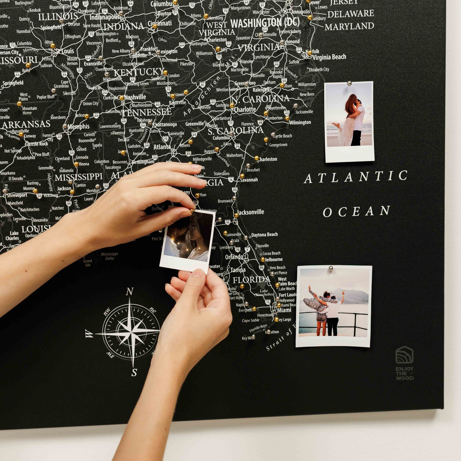 Map of the United States with pins and a person holding photos on a black background