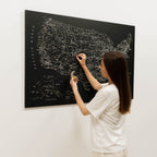 Person scratching off a map of the United States on a blackboard-style wall map.
