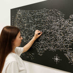 Woman interacting with a large black map of the United States on a wall.