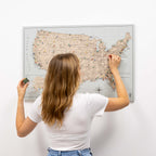Woman scratching a map of the United States on a white wall