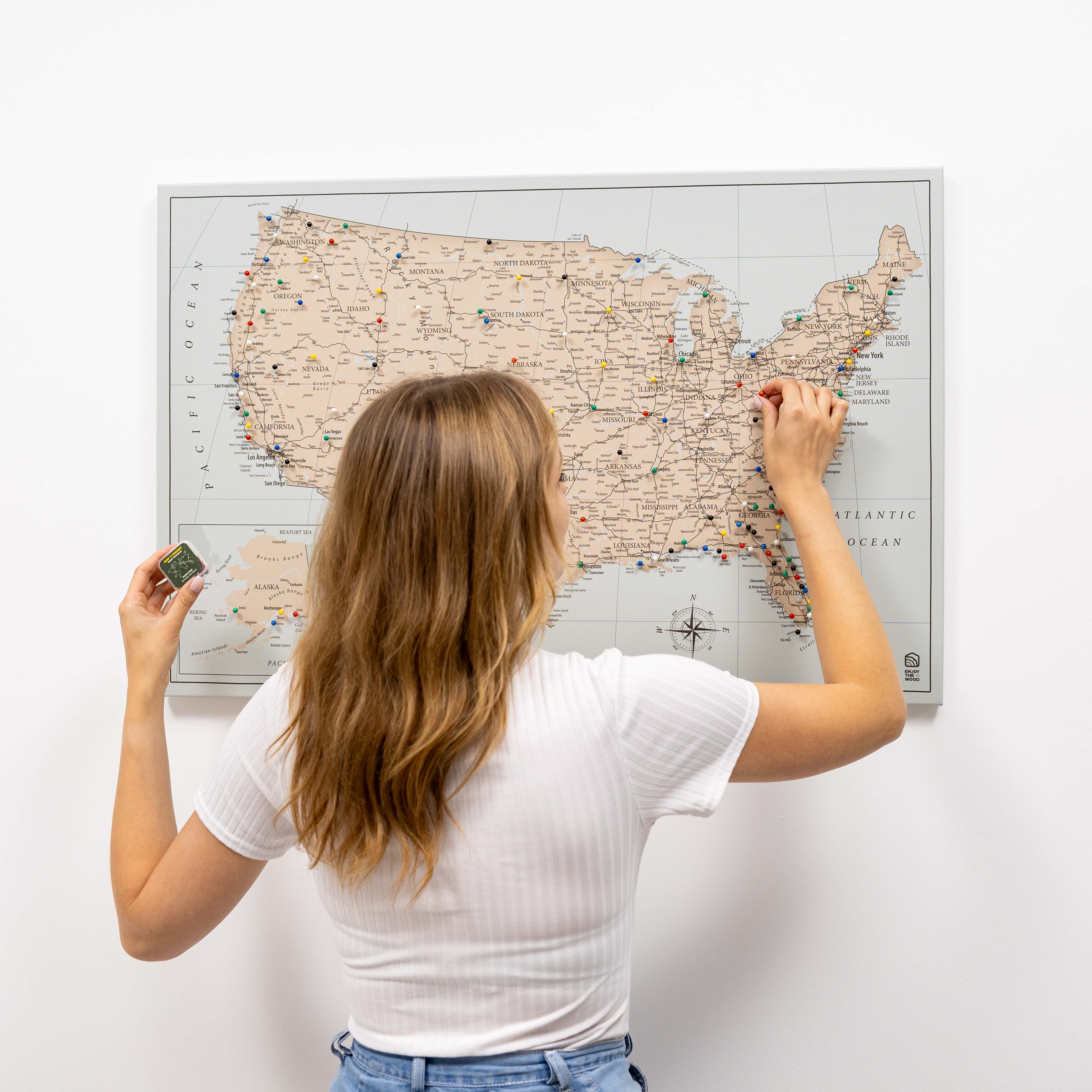 Woman scratching a map of the United States on a white wall