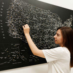 Woman interacting with a large black map of the United States on a wall.