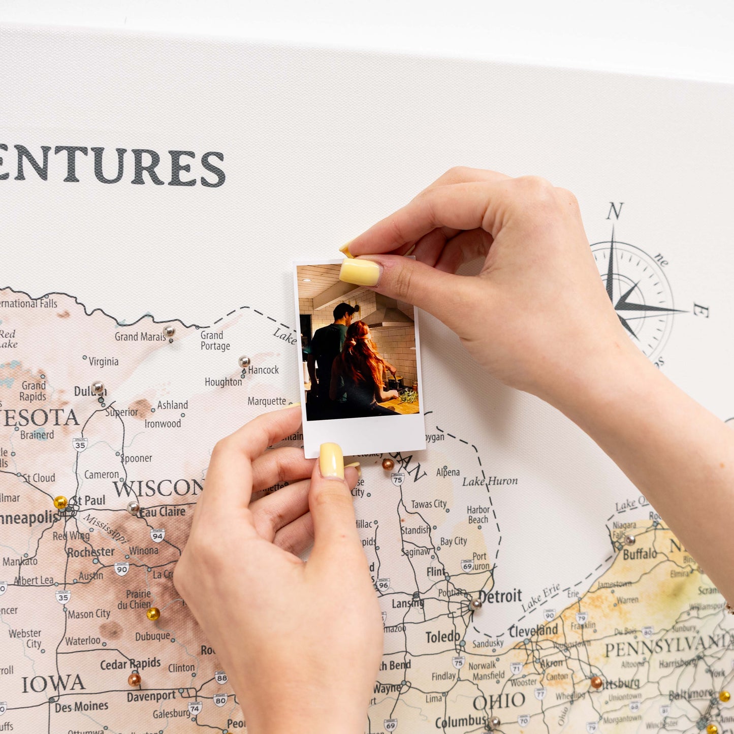 Person holding a photo over a map with 'ENTURES' text