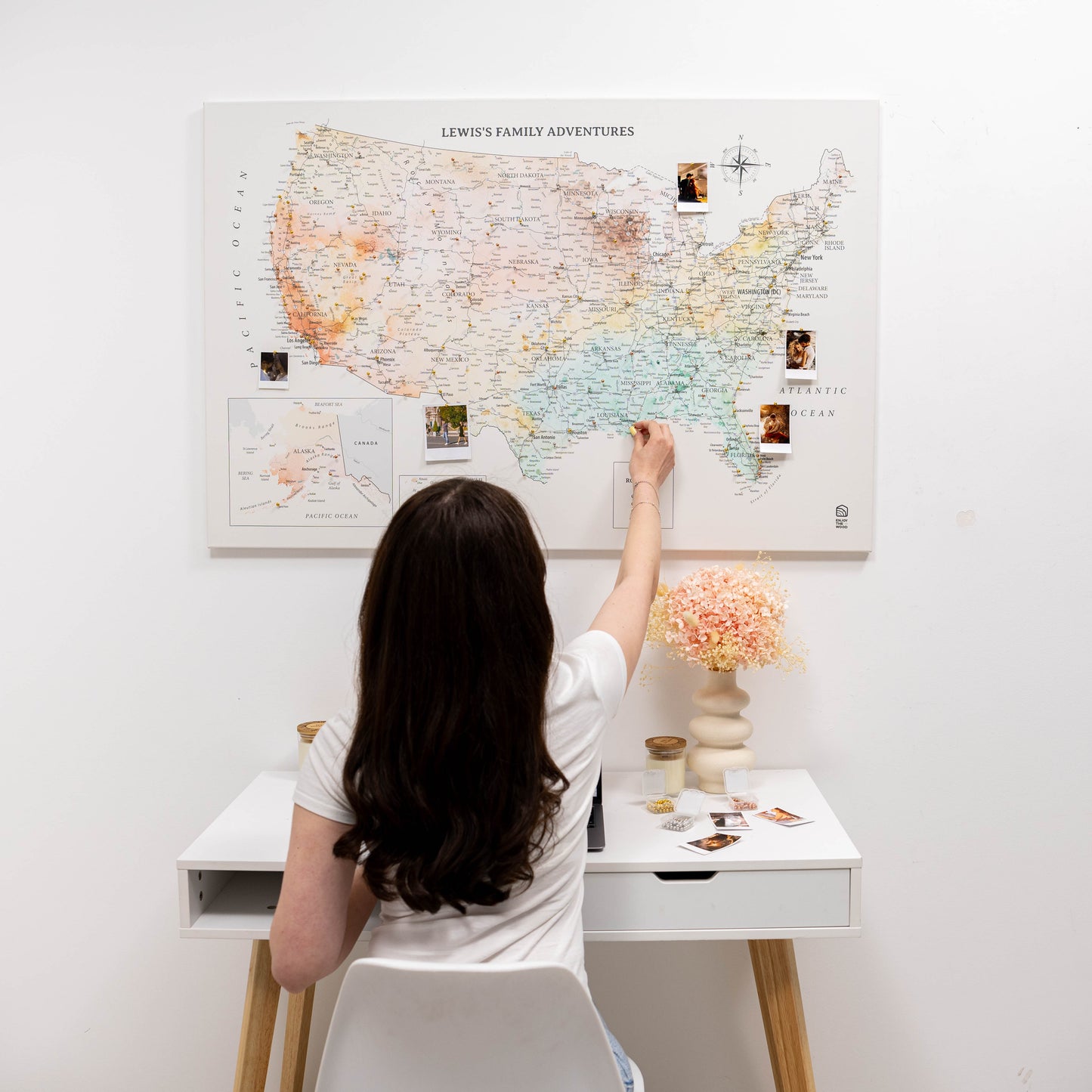 Person interacting with a large map of the United States on a wall, with a small table and decorative items in the foreground.