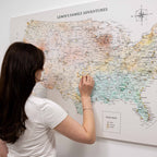 Woman marking a location on a world map titled 'Lewis's Family Adventures'.