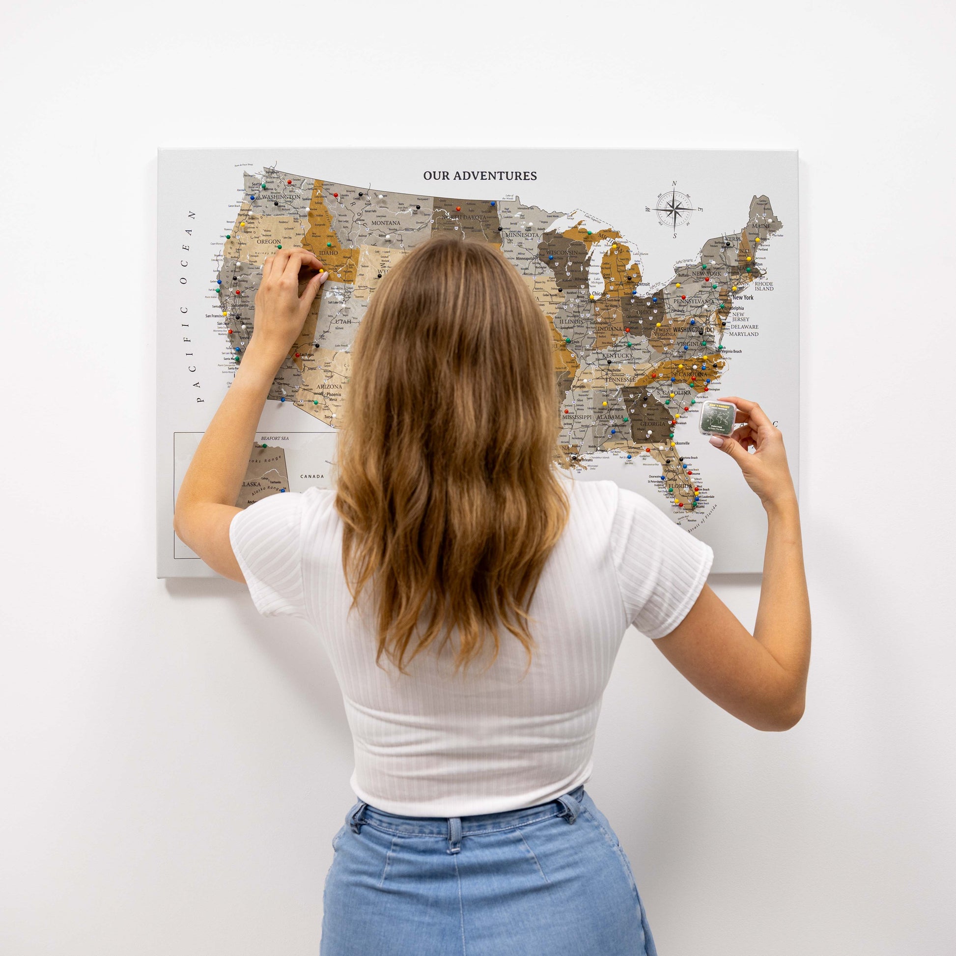 Woman marking a location on a map of the United States with pins.