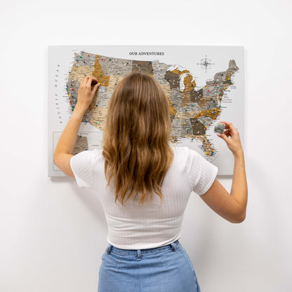 Woman marking a location on a map of the United States with pins.