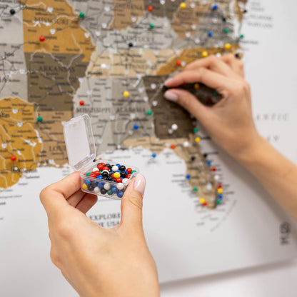 Person holding a container of colorful pins over a map