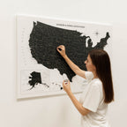 Woman marking a location on a map of the United States with pins.
