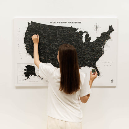 Person scratching a map of the United States on a wall with 'Andrew & Emma Adventures' text.