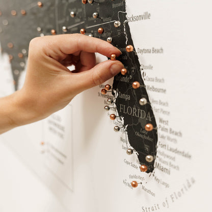 Hand holding a decorative item with beads over a map of Florida.