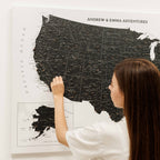 Woman looking at a large map of the United States with 'Andrew & Emma Adventures' text.