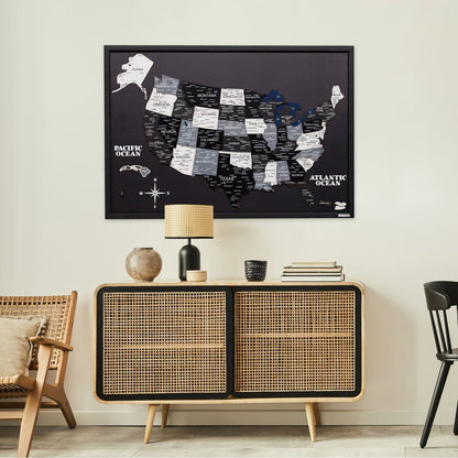 Framed map of the United States on a wall above a wooden cabinet in a room.