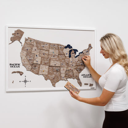 Woman interacting with a framed map of the United States on a white wall