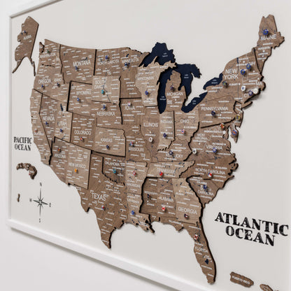 Wooden map of the United States with pins on a white background