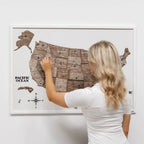 Woman interacting with a wooden map of the United States on a white wall
