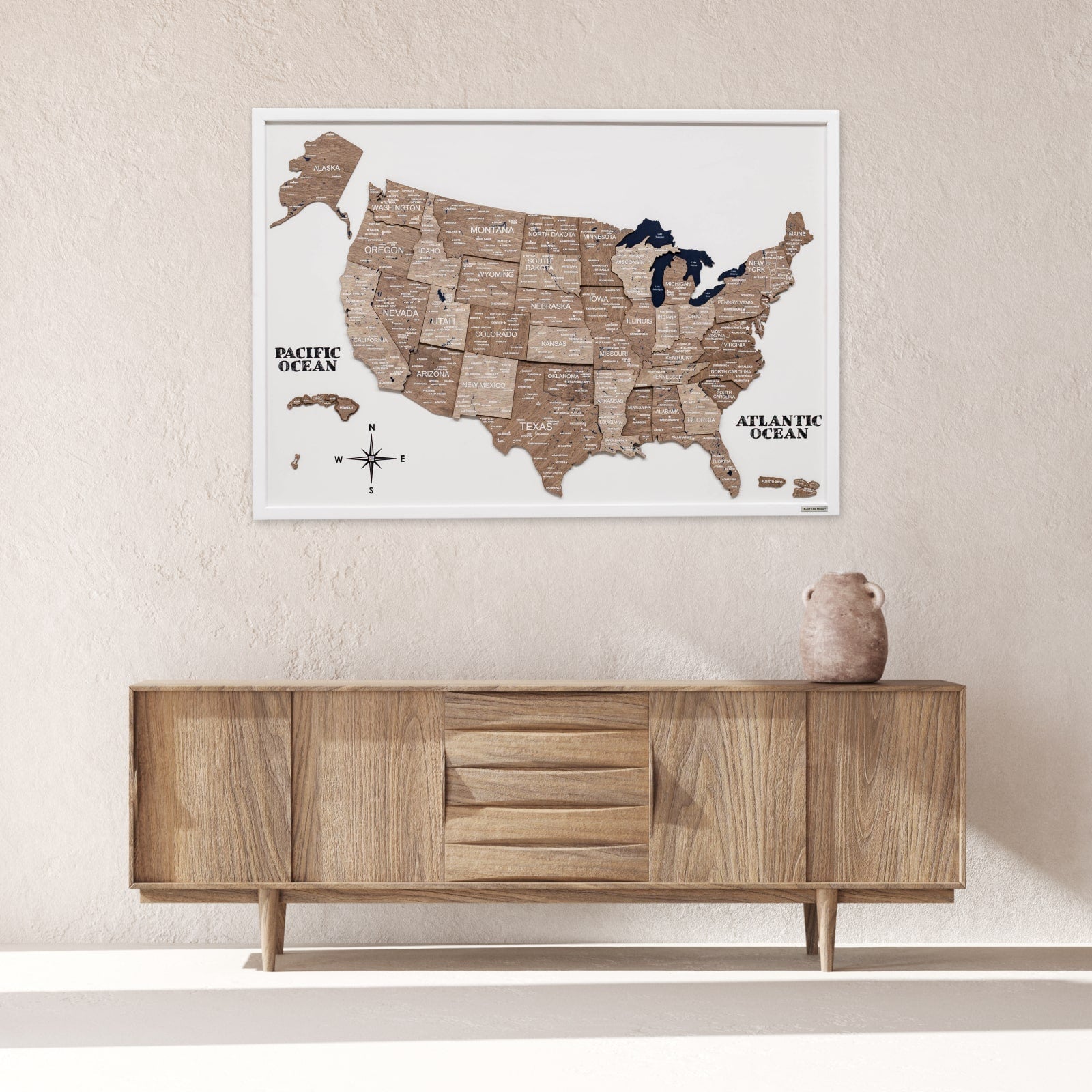 Wooden map of the United States on a wall above a wooden cabinet.