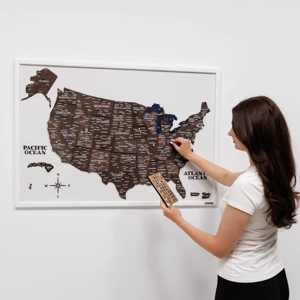 Woman scratching a map of the United States on a white wall