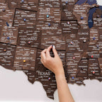 Hand interacting with a wooden map of the United States on a white background