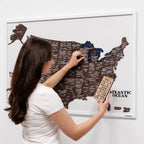 Woman interacting with a map of the United States on a wall, using a remote control.