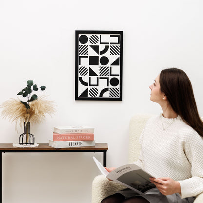 Woman reading a book in a living room with geometric art on the wall.