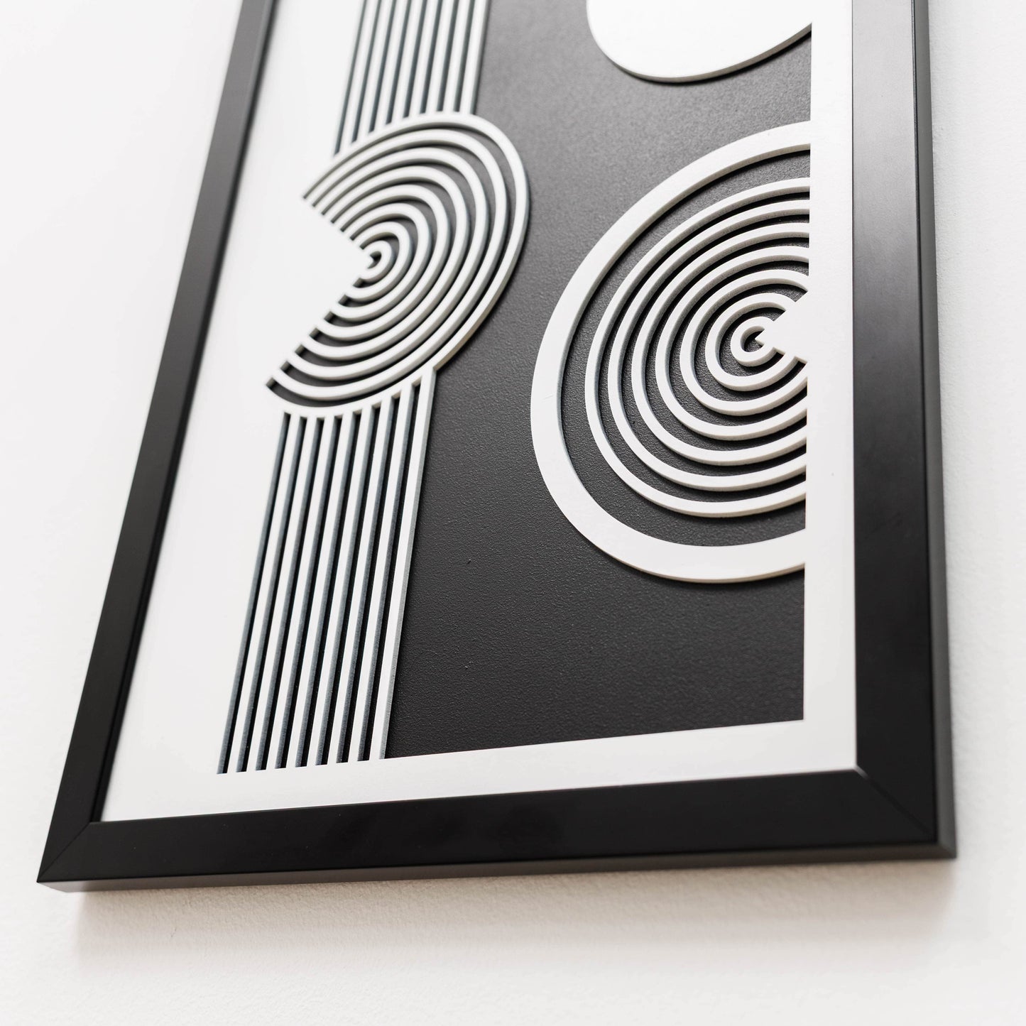 Framed black and white abstract art piece on a white background