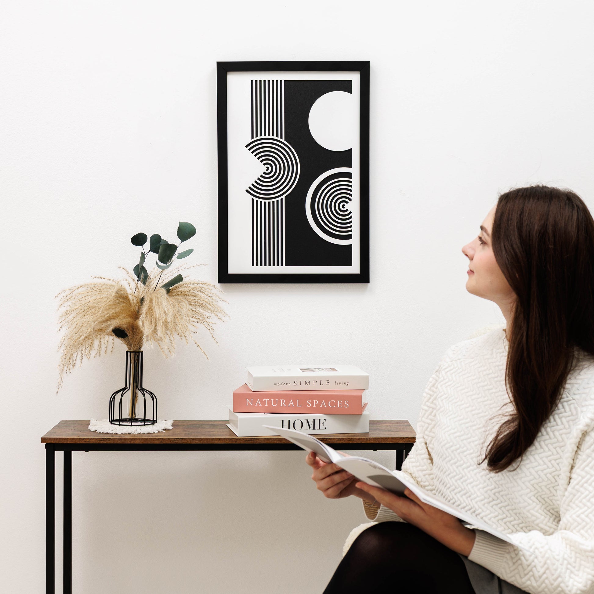Woman sitting in a room with a modern abstract art piece on the wall.