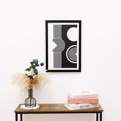 Framed abstract art piece on a wall above a wooden table with decor items.