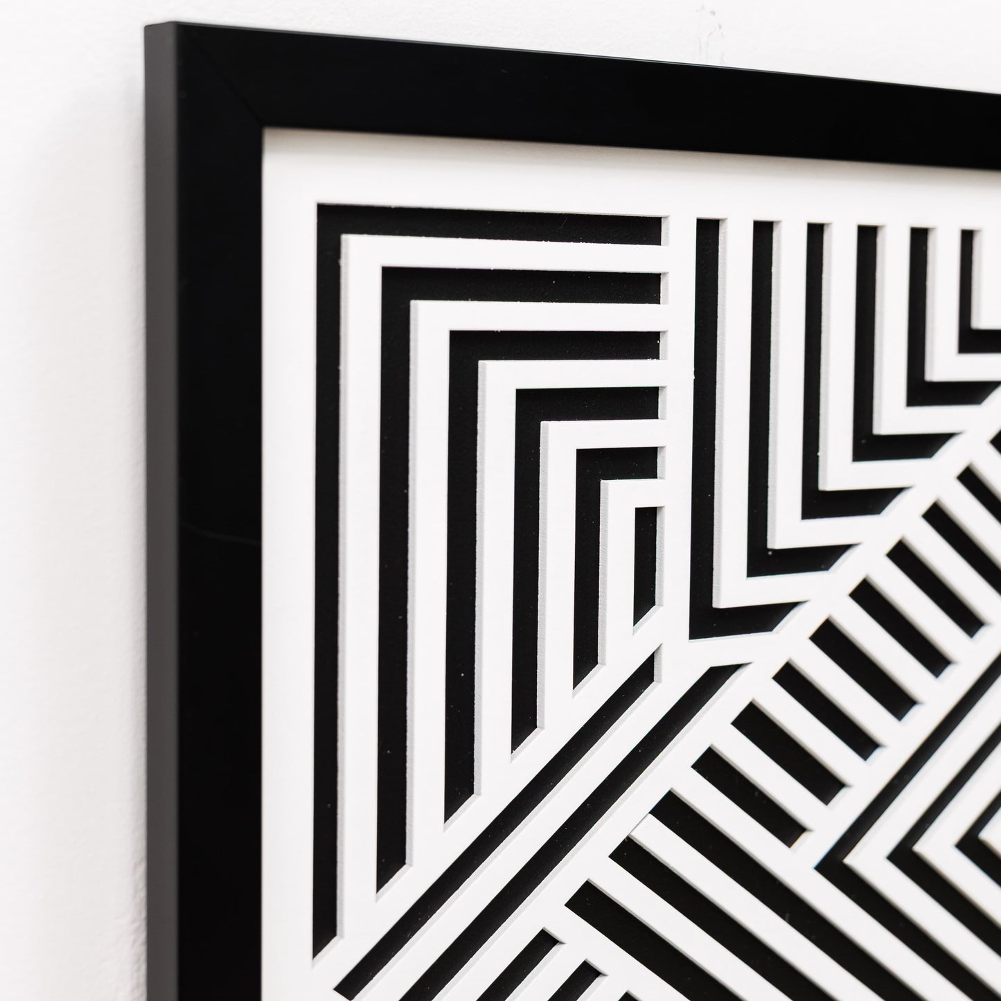 Framed black and white geometric pattern on a white wall
