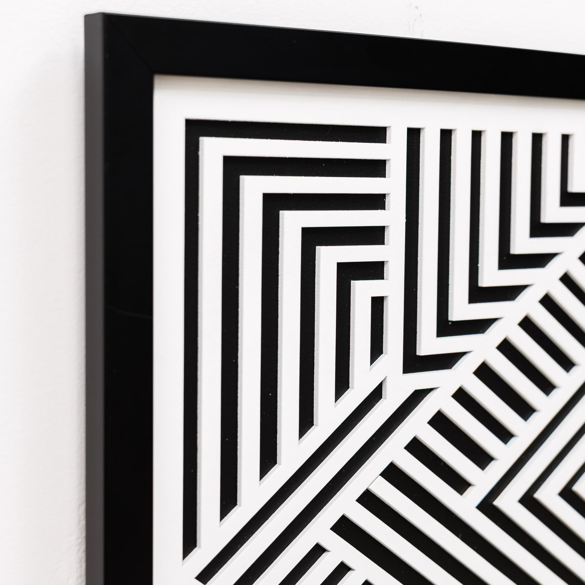 Framed black and white geometric pattern on a white wall