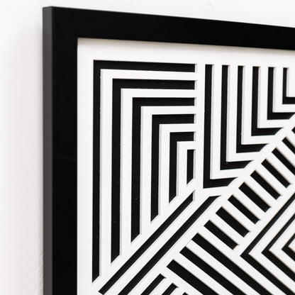 Framed black and white geometric pattern on a white wall