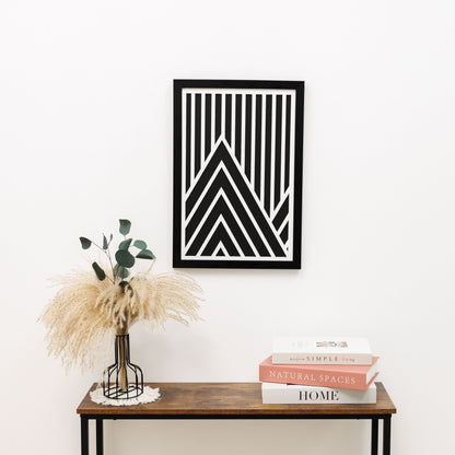 Framed geometric art piece on a wall above a wooden console table with decor items.