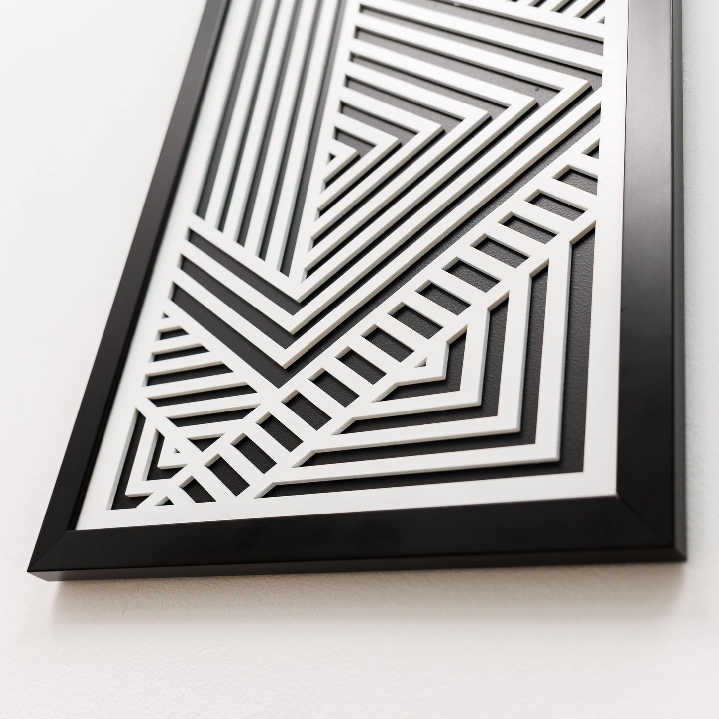 Framed black and white geometric art piece on a light background
