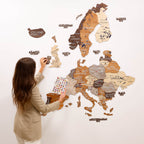 Woman interacting with a wooden world map on a white wall
