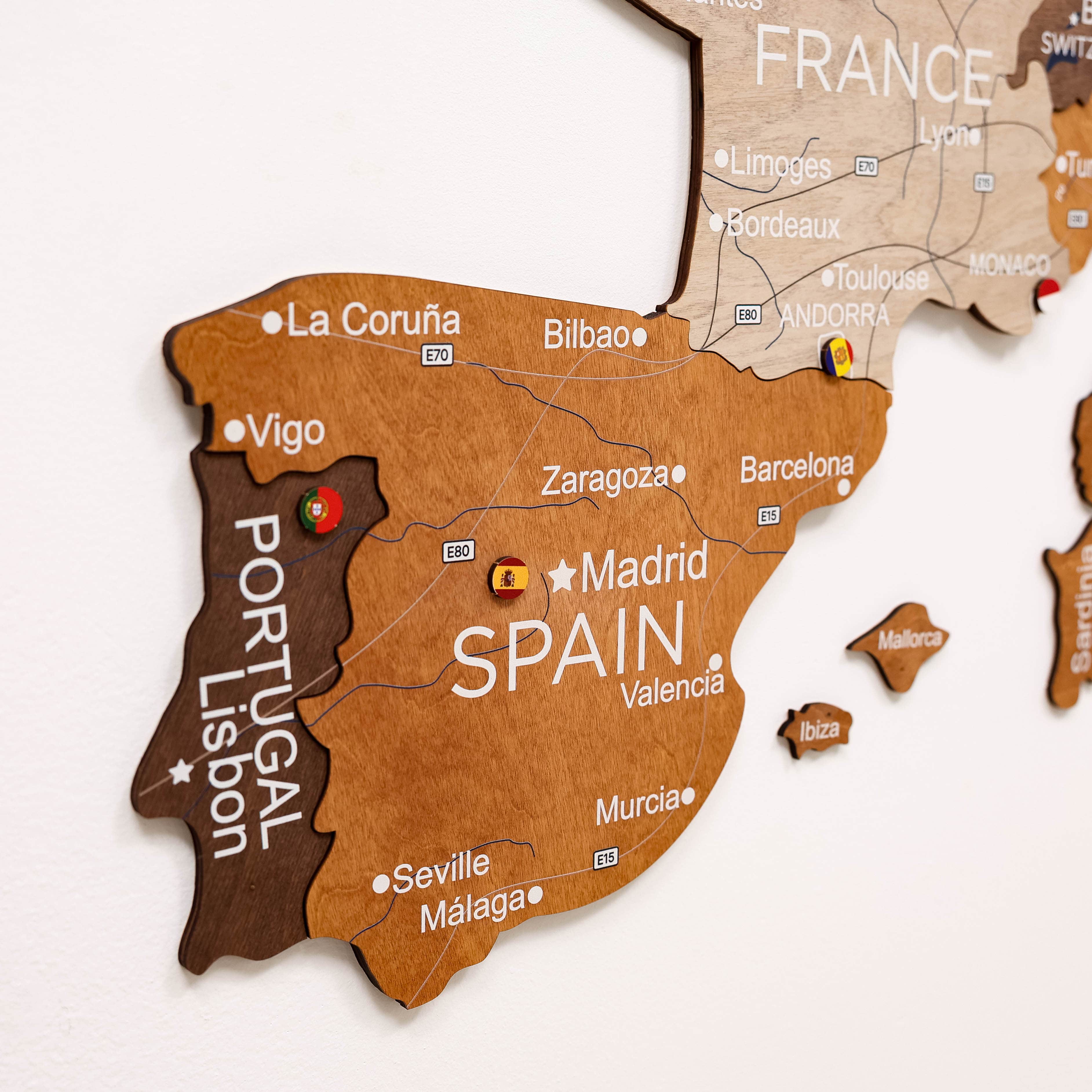 Wooden map of Spain with cities labeled on a white background