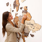 Woman assembling a wooden map of Europe on a white wall