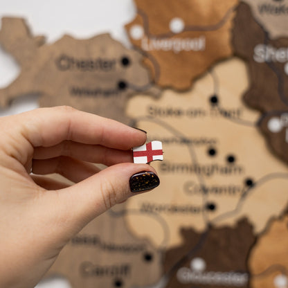 Hand holding a small flag in front of a wooden map