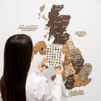 Woman interacting with a wooden map of Scotland on a white background